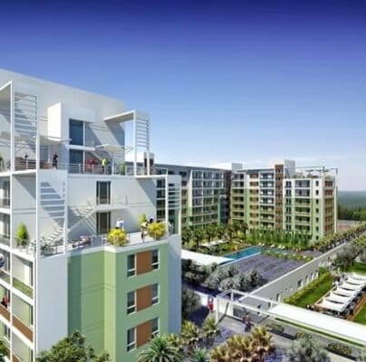 Balkon ve çatı terasları bulunan birden fazla orta yükseklikte apartman binasının bulunduğu çağdaş bir konut kompleksi. Merkezi avluda yüzme havuzu, peyzajlı bahçeler ve gölgeli yürüyüş yolları bulunmaktadır. Binalar açık mavi gökyüzünün altında çeşitli yeşil ve beyaz tonlarında boyanmıştır.