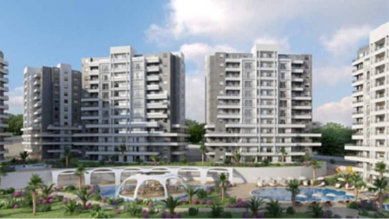 Çağdaş mimariye sahip çok sayıda yüksek katlı binadan oluşan modern bir konut kompleksi. Alanda peyzajlı bahçeler, yüzme havuzu ve dinlenme tesisleri bulunmaktadır. Gökyüzü kısmen bulutludur ve arka planda ağaçlar ve yeşillikler görülmektedir.